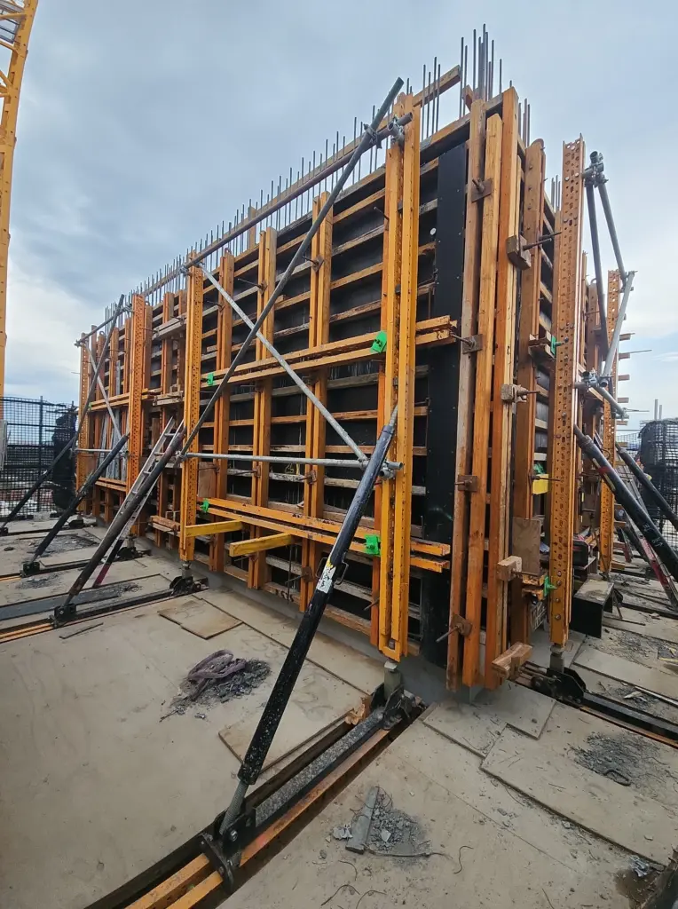 Concrete wall formwork structure supported by adjustable metal props on a construction site